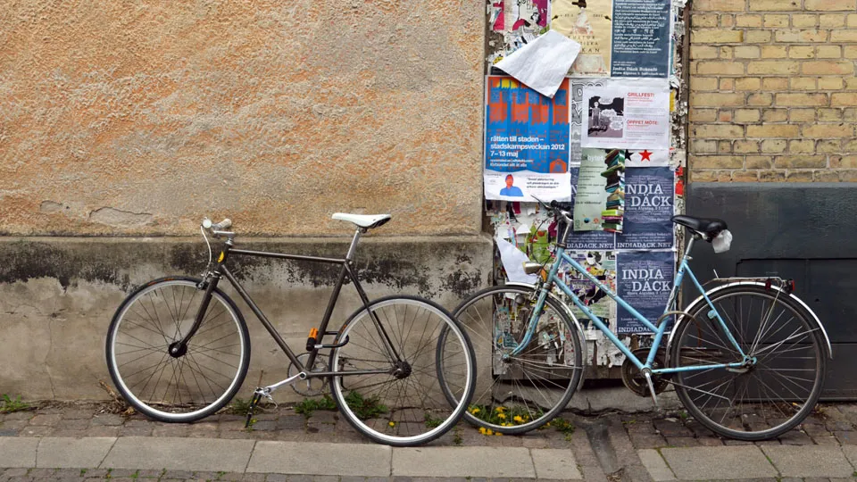 Two bicycles parked against a wall. Photo.