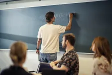 En student på kandidatutbildningen i livsmedelsteknik ses bakifrån när han skriver på undervisningstavlan.